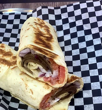 East Coast style beef donair wrap with onion and tomato on checkered paper